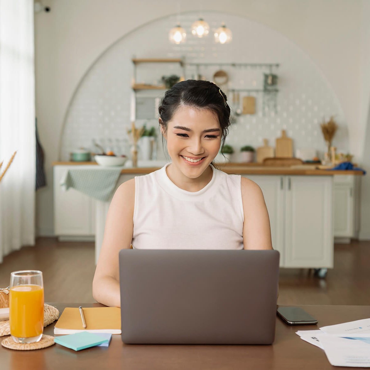 beautiful-young-asian-woman-working-laptop-computer-while-sitting-kitchen-room-background